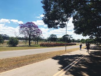 People walking on road in city against sky