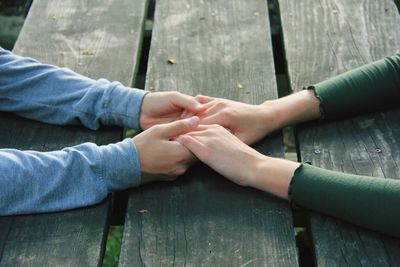 Cropped image of couple holding hands at wooden table