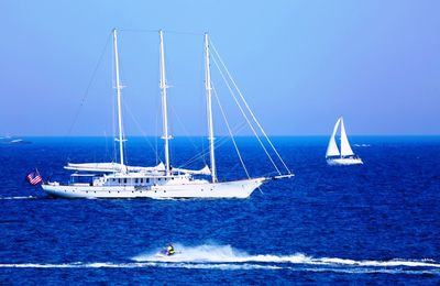 Sailboat on sea against clear blue sky