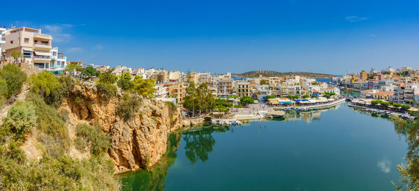 High angle view of houses by sea against clear blue sky