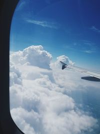 Aerial view of clouds and sky seen through airplane window