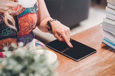 Close-up of woman using smart phone on table
