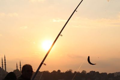 Silhouette people flying against sky during sunset