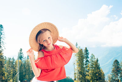 Young woman wearing hat standing against sky