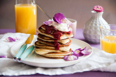 Close-up of pancakes with juice served on table