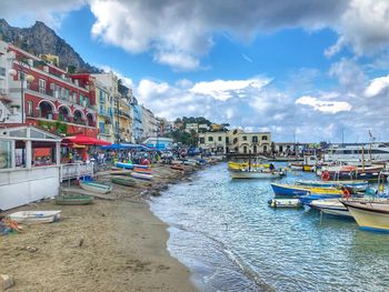 Boats moored at harbor against buildings in city