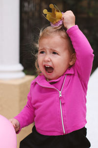 Cute girl holding crown while crying