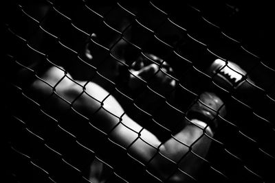 Shirtless boxer seen through chainlink fence