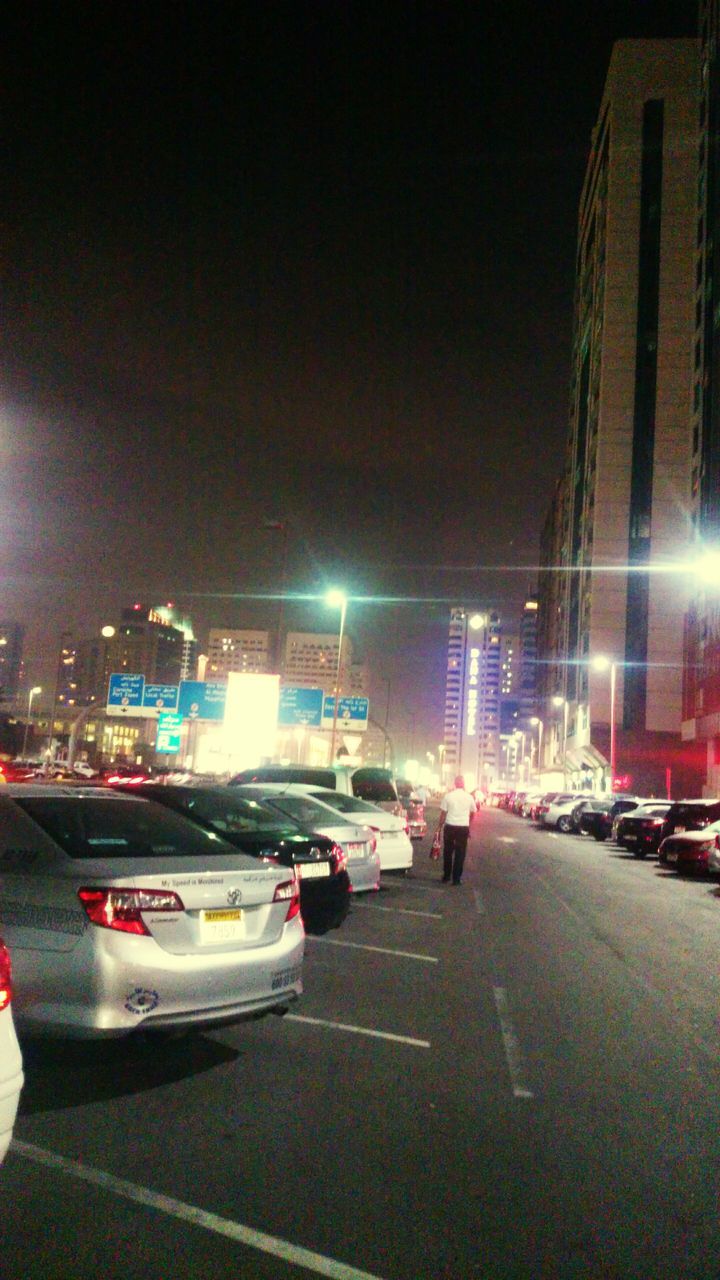 ROAD PASSING THROUGH ILLUMINATED CITY AT NIGHT