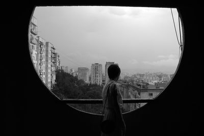 Rear view of woman looking through cityscape against sky