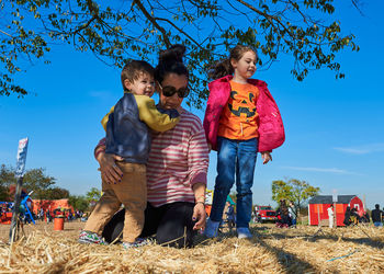 Mom with kids on top of a hay stack at the farm fair on halloween