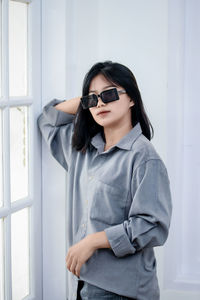 Portrait of young woman wearing sunglasses while standing at home