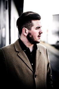 Close-up of young man standing against car in city