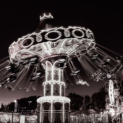 Low angle view of illuminated carousel against sky at night