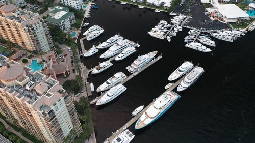 High angle view of sailboats moored on sea by buildings in city