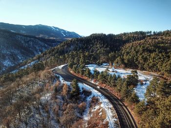 Aerial view of road by mountains against clear sky