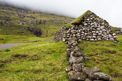 Stone wall on land against sky