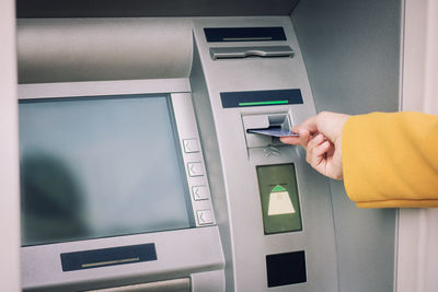 Cropped hand of woman inserting card in atm machine