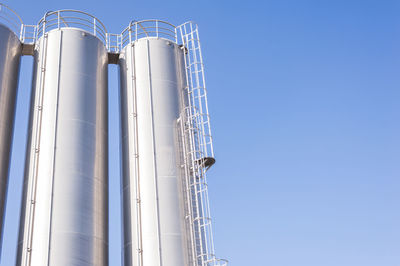 Low angle view of storage tanks against clear sky