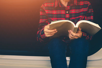 Midsection of woman reading book