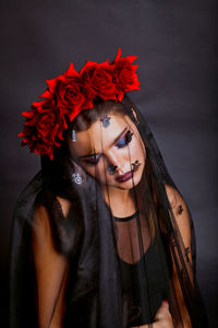 Young woman covered with fabric against black background