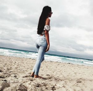 Full length of young woman standing on beach