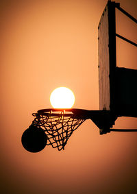 Low angle view of silhouette basketball hoop against orange sky during sunset