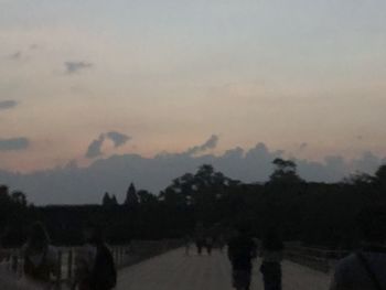 Silhouette trees on landscape against sky at sunset