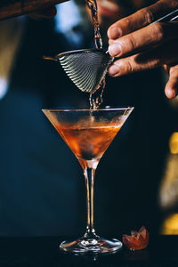 Midsection of bartender preparing cocktail in bar