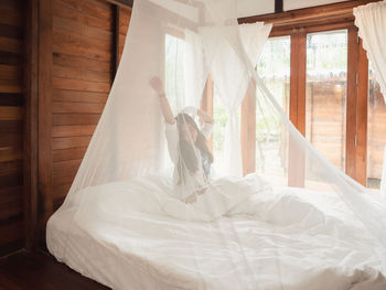 Woman stretching in bed after wake up, happy greets new day with warm sunlight.