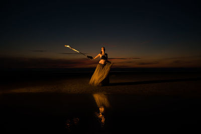 Silhouette woman standing on beach against sky during sunset