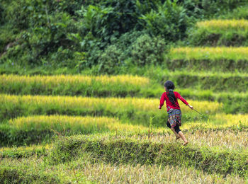 Rear view of girl running on field