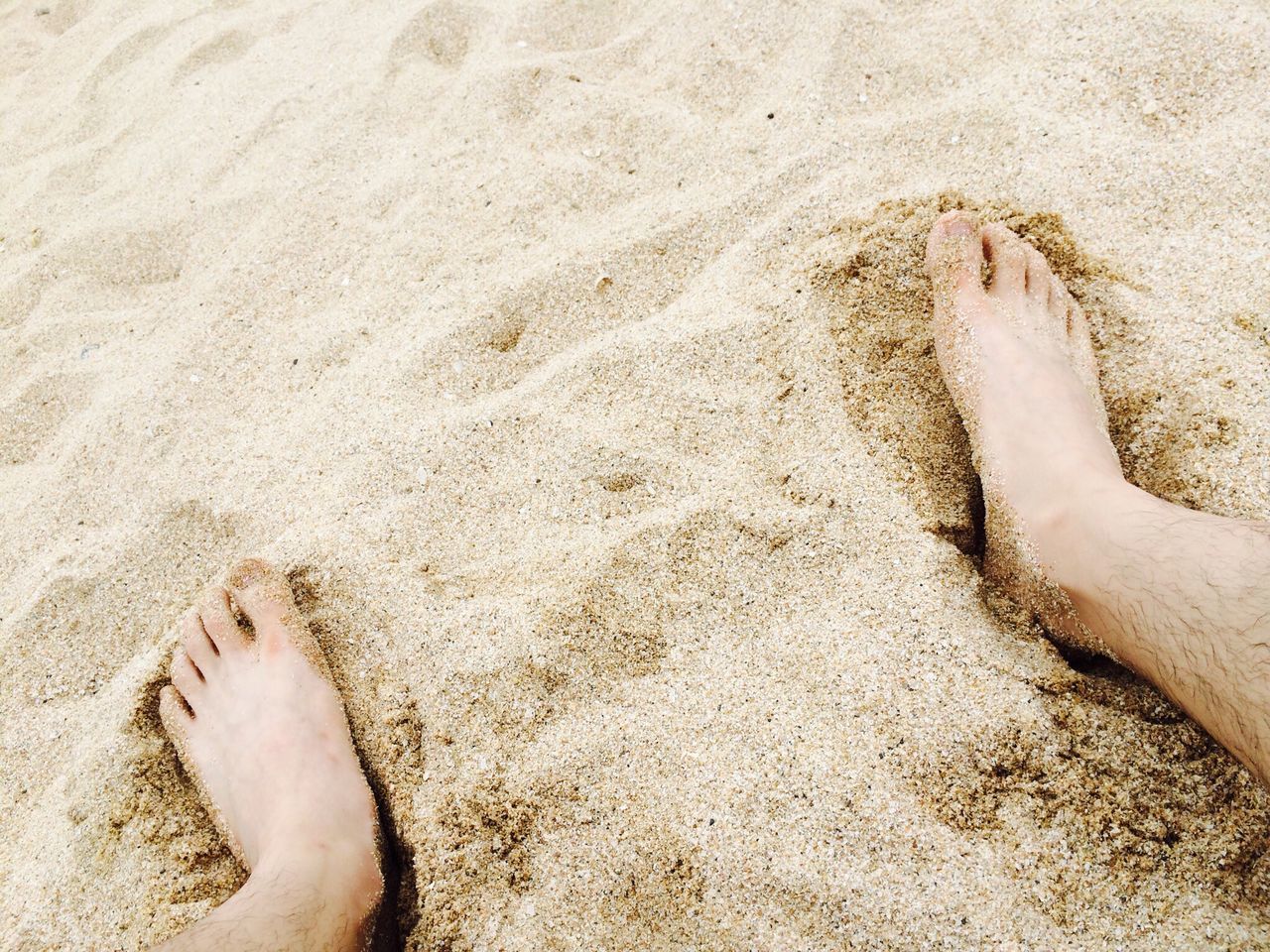 low section, person, sand, beach, barefoot, human foot, personal perspective, lifestyles, leisure activity, shore, high angle view, relaxation, water, sunlight, sea, vacations