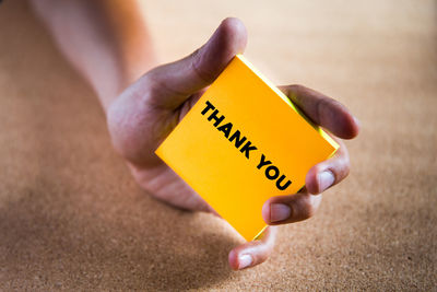 Cropped hand holding yellow sticky note with thank you text
