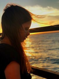 Woman looking at sea against sky during sunset