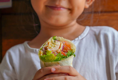 Midsection of woman holding wrap salad