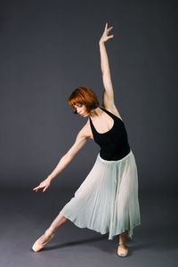 Ballerina dancing against gray backdrop