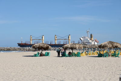 People on beach by building against sky