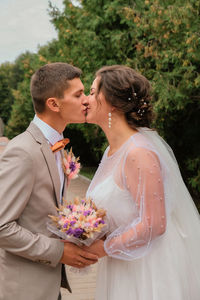 Groom hug and kiss bride in palm grove. wedding day for two. lovely weeding couple. young lovers. 