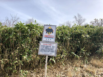 Information sign on field against sky