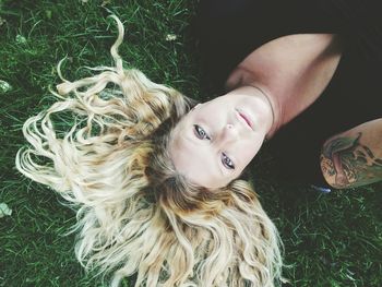 High angle portrait of smiling woman lying down on land