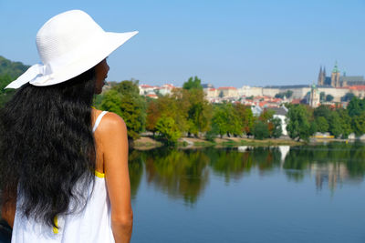 Rear view of woman looking at lake against clear sky