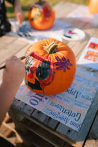 Close-up of child hands while painting pumpkin for halloween