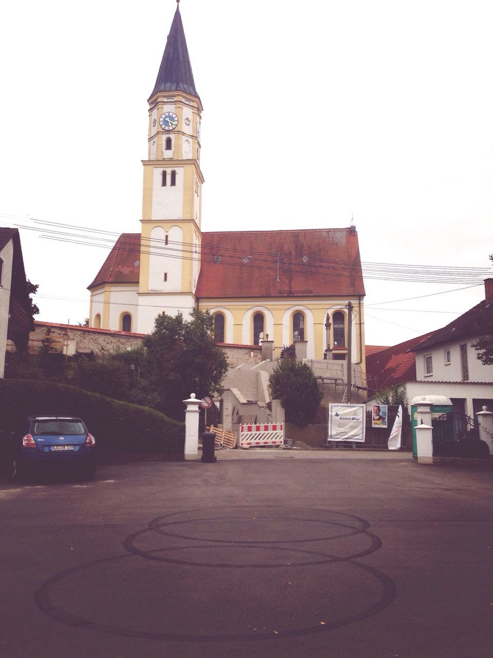 building exterior, architecture, built structure, church, religion, place of worship, street, clear sky, spirituality, sky, road, low angle view, car, transportation, city, clock tower, incidental people, facade