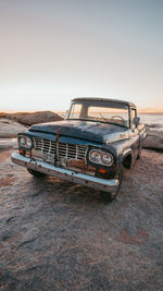 Abandoned car on land against sky