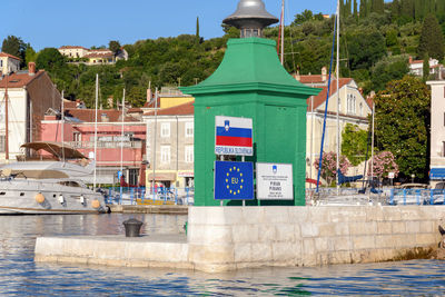 Border crossing sings in front of green lighthouse in port of piran in slovenia