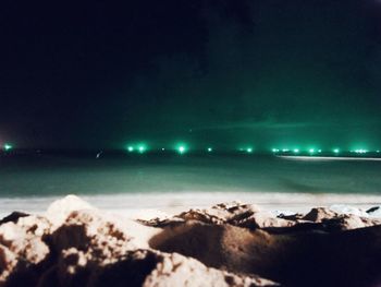 Rocks on beach against sky at night