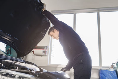 Mechanic opening car's hood in auto repair shop