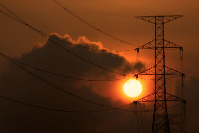 Low angle view of silhouette electricity pylon against sky during sunset