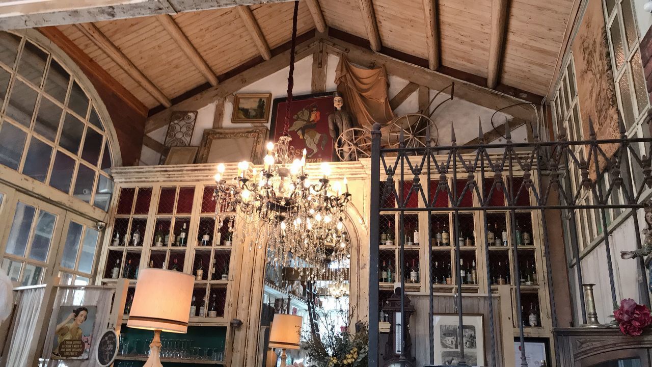 LOW ANGLE VIEW OF ILLUMINATED PENDANT LIGHTS HANGING ON CEILING IN RESTAURANT